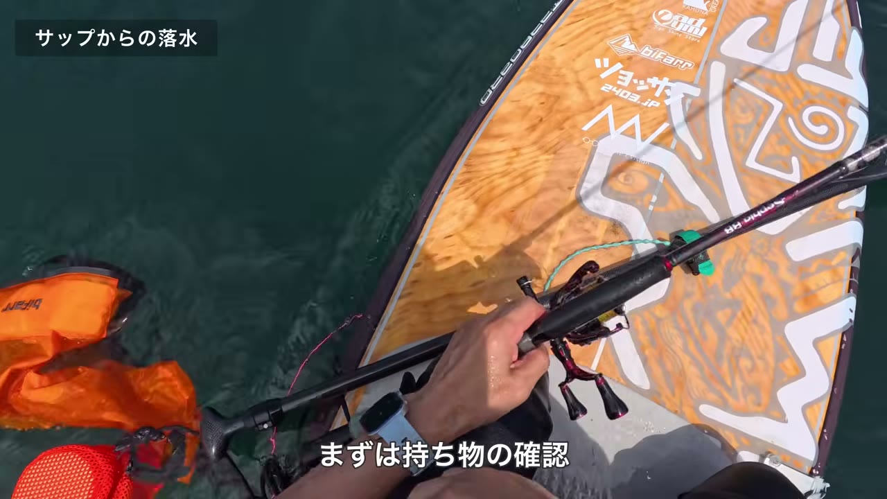 落水したあと、SUPの横で持ち物を確認している場面