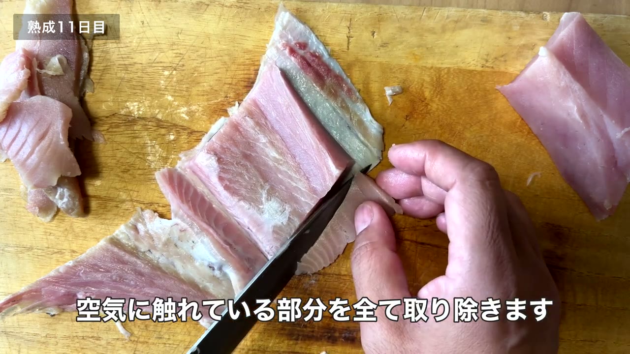 熟成11日目のコシナガマグロをまな板で切り分ける手元